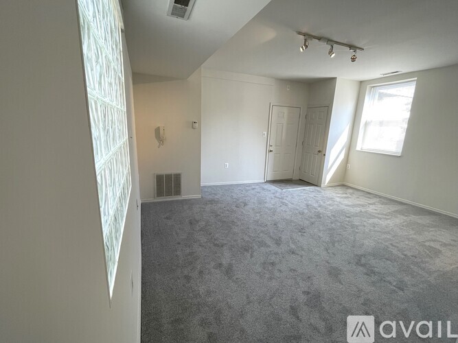 A room with a carpeted floor and a window letting in natural light.
