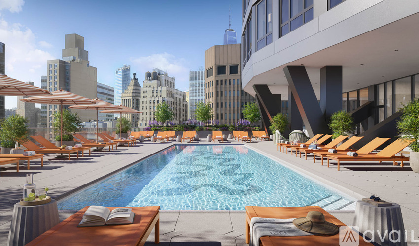 A pool area with sun loungers and a city skyline in the background.