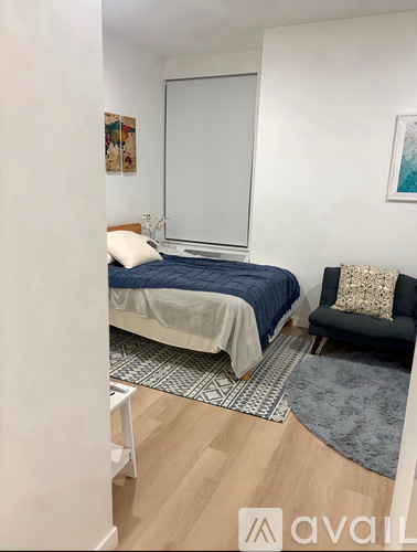 A bedroom with a bed, chair, and a rug.