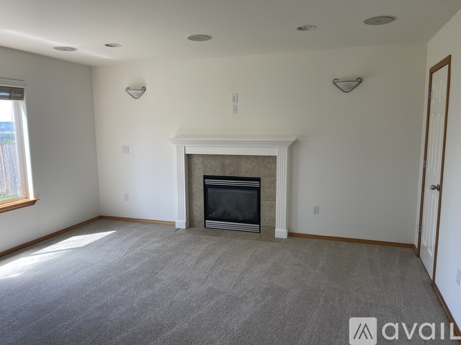 A living room with a fireplace and carpeted floor.