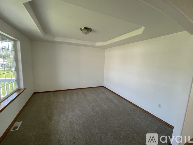 A room with a window on the left side and a carpeted floor.