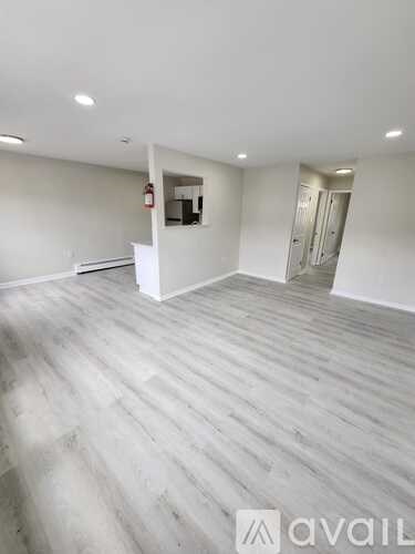 A spacious room with wooden flooring and white walls.