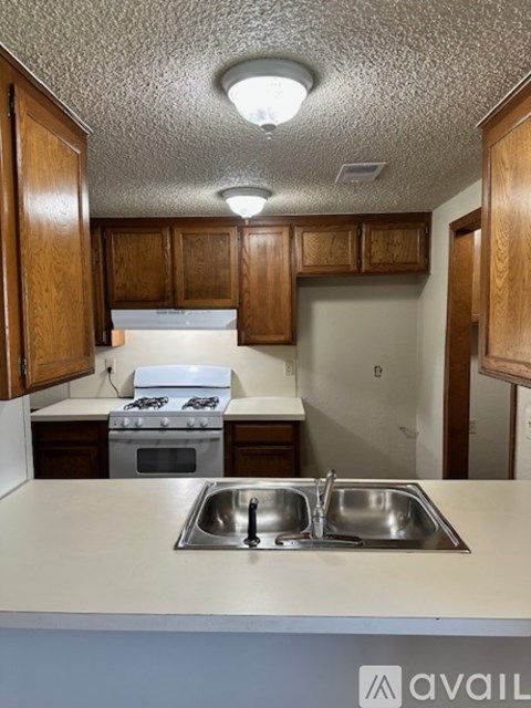 A kitchen with a stove, sink and cabinets.
