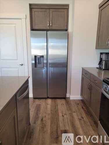 A kitchen with a stainless steel refrigerator and wooden floors.