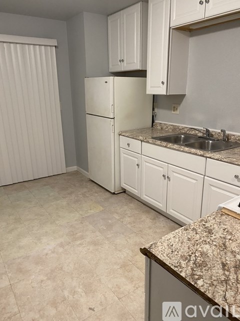 A kitchen with white cabinets and a granite counter.