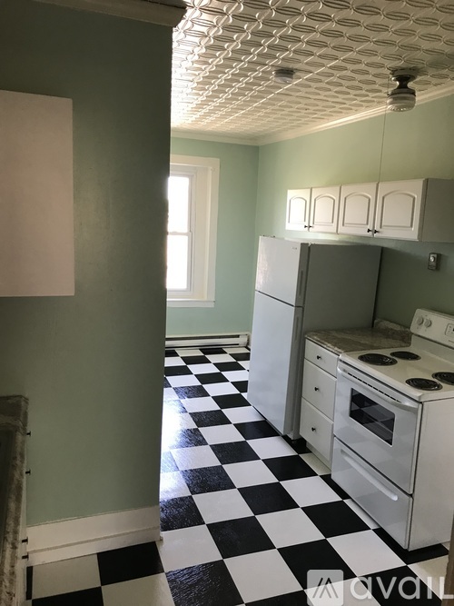 A kitchen with a checkered floor and white appliances.