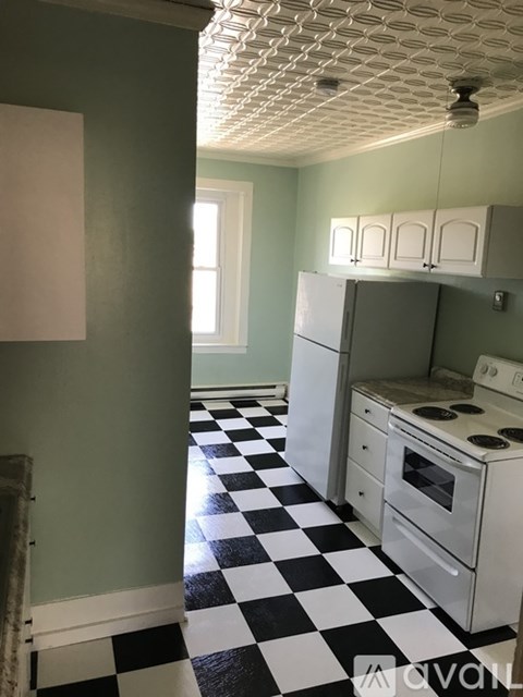 A kitchen with a checkered floor and white appliances.