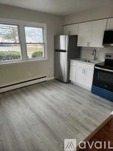 A kitchen with a refrigerator, cabinets, and a window.
