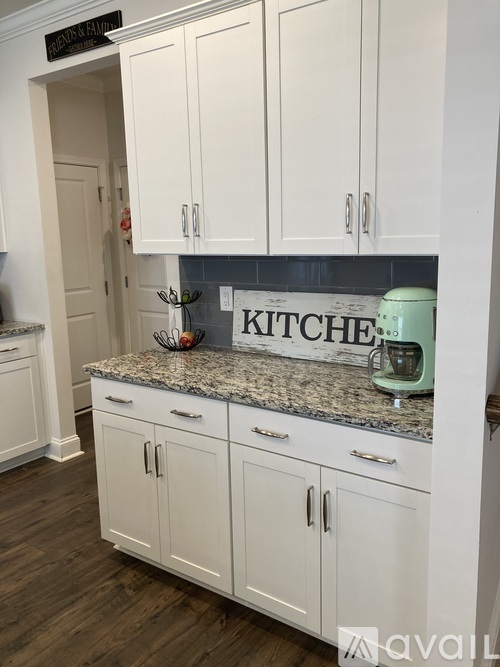 A kitchen with white cabinets and a granite countertop.