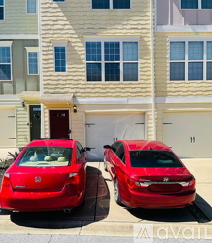 Two red cars parked in front of a two-story building.
