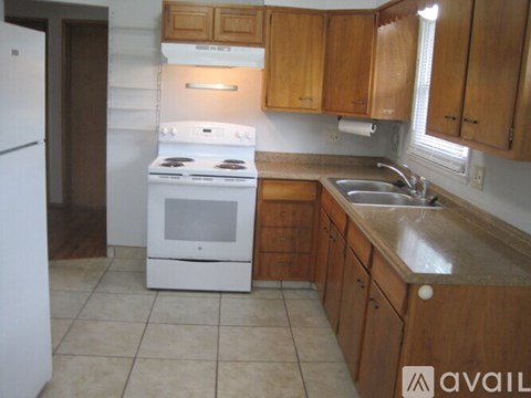 A kitchen with wooden cabinets and a white stove top oven.