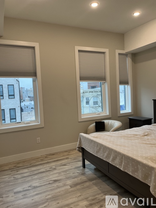 A bedroom with a bed, nightstand, and two windows.