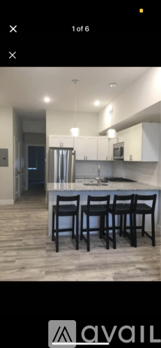 A kitchen with a bar stool and a fridge.