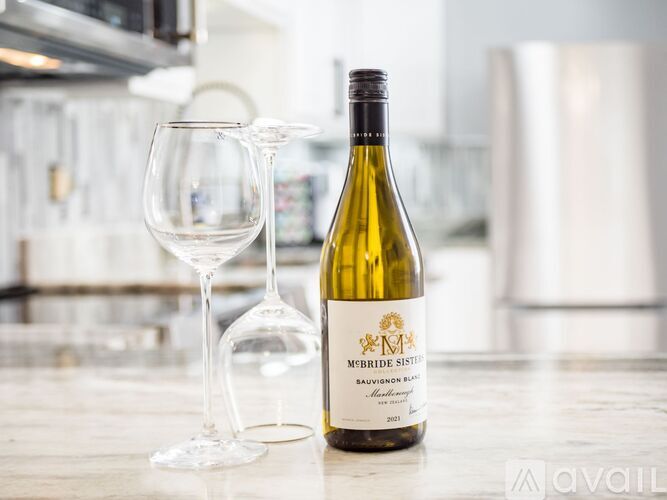 A bottle of Sauvignon Blanc wine and a glass are on a counter.