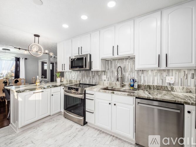 A modern kitchen with white cabinets and a marble countertop.