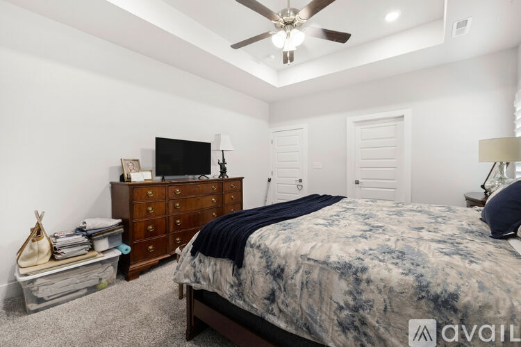 A bedroom with a bed, dresser, and ceiling fan.