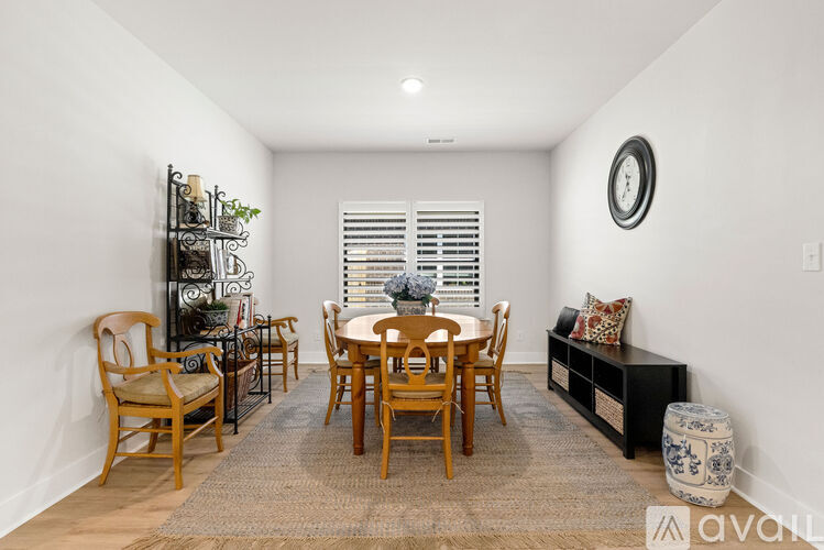 A dining room with a table set for four and a clock on the wall.