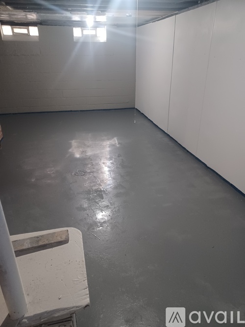 A large empty room with a concrete floor and white walls.