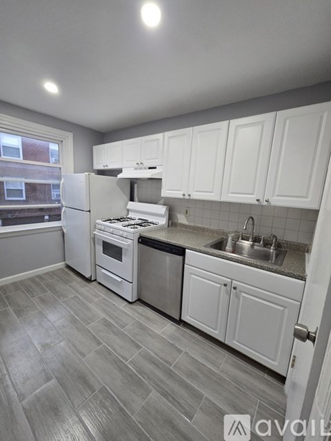 A kitchen with white cabinets and a grey floor.