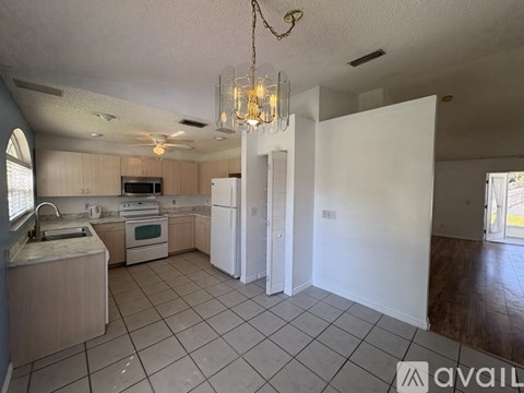 A kitchen with a white refrigerator and a chandelier hanging from the ceiling.