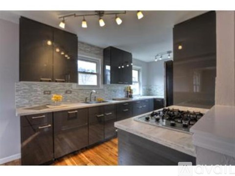 A modern kitchen with dark wood cabinets and a marble backsplash.