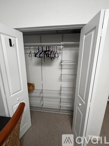 A white closet with clothes hanging on a rail.