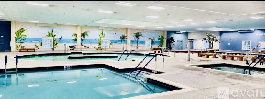 A large indoor swimming pool with a mural of a beach scene on the wall.