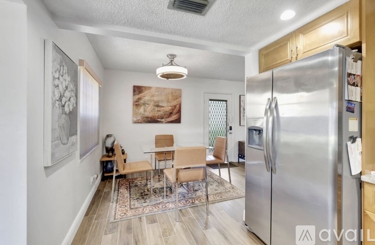 A kitchen with a refrigerator, table and chairs.