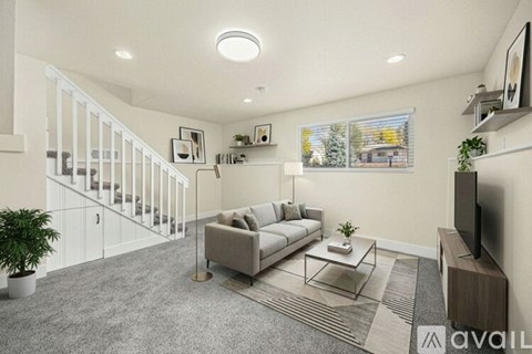 A living room with a grey sofa and a television on the right side.