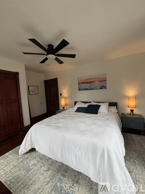 A bedroom with a large bed and a ceiling fan.