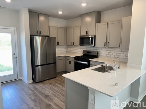 A kitchen with a refrigerator, microwave, oven, and sink.