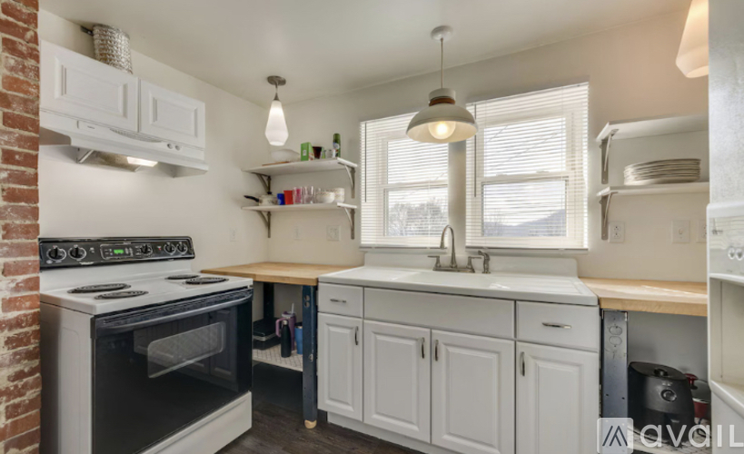 A kitchen with white cabinets and a brick wall.