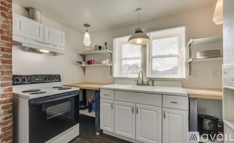 A kitchen with white cabinets and a brick wall.