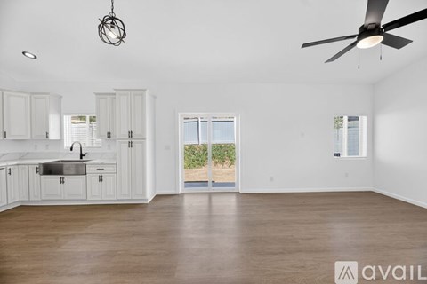 A spacious kitchen with white cabinets and a wooden floor.