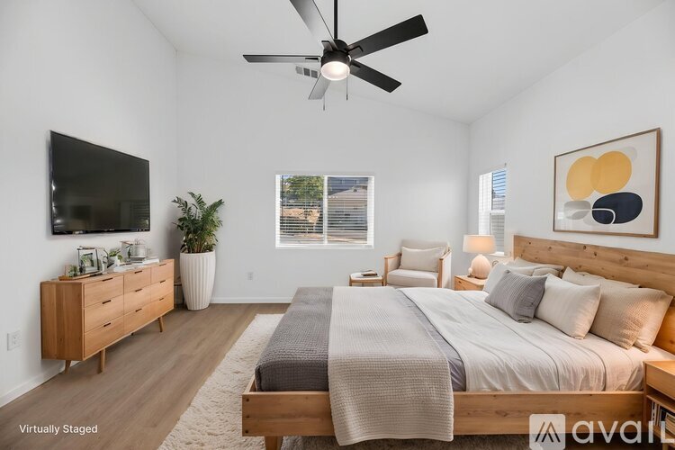 A bedroom with a large bed, a flat screen TV, and a ceiling fan.