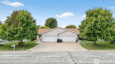 A house with a driveway and trees in front of it.