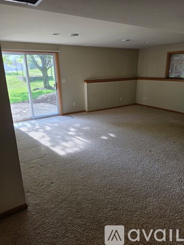 A spacious room with a carpeted floor and a sliding glass door leading to a garden.