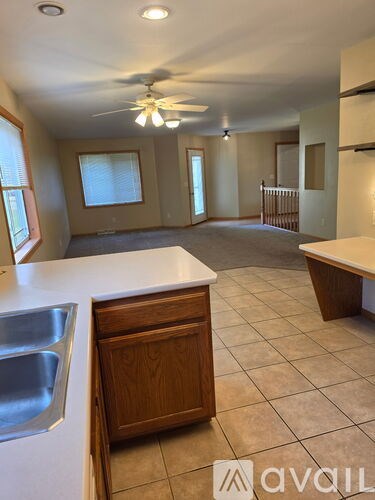 A kitchen with a sink, stove and a fan.