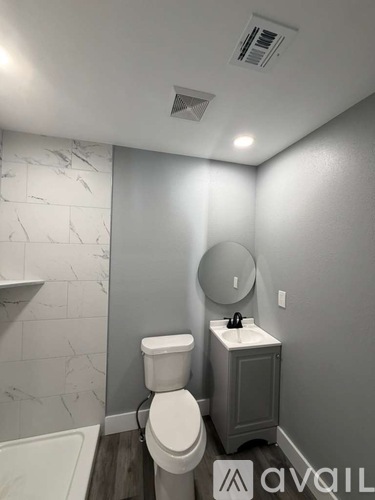 A bathroom with a toilet, sink, and mirror.