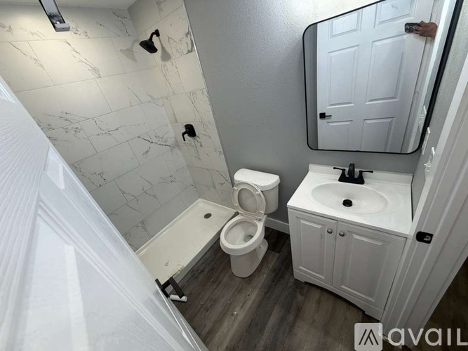 A bathroom with a toilet, sink, and mirror.