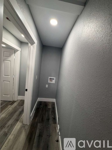 A hallway with a wooden floor and white walls.