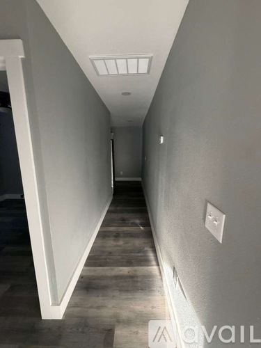 A long, narrow hallway with a light on the ceiling and a wall on the right.