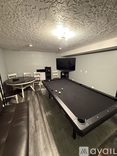 A room with a pool table and a TV mounted on the wall.