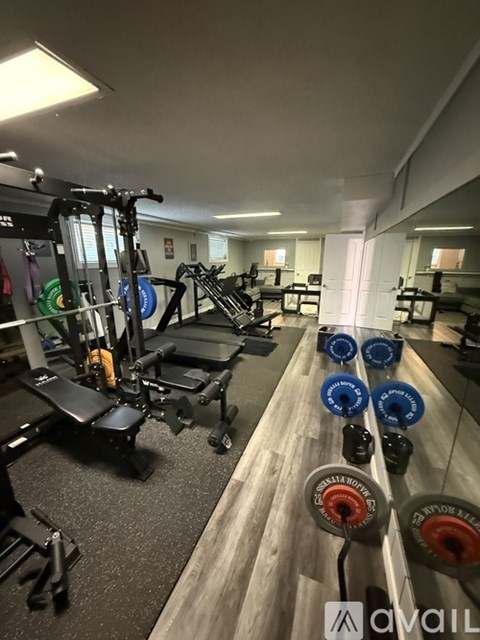 A gym with a variety of equipment including weight plates and a bench press.