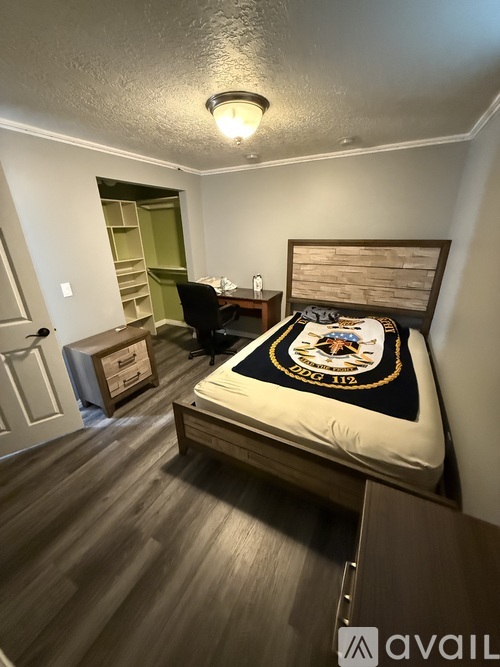 A bedroom with a bed, chair, and a small desk.