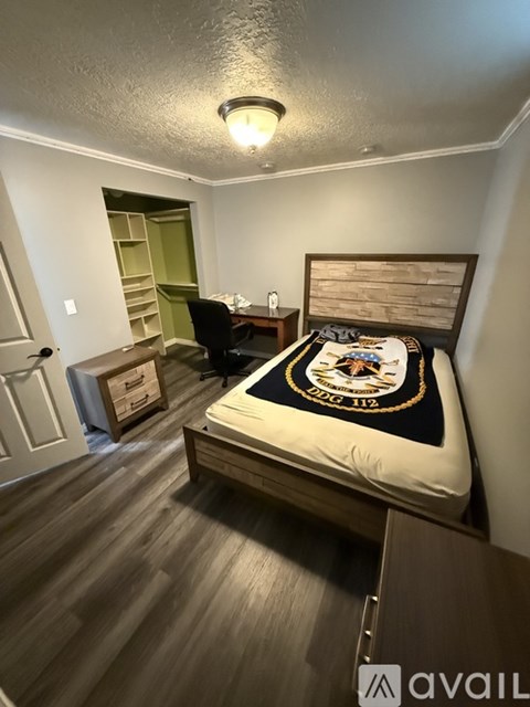 A bedroom with a bed, chair, and a small desk.