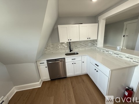 A kitchen with white cabinets and a wooden floor.
