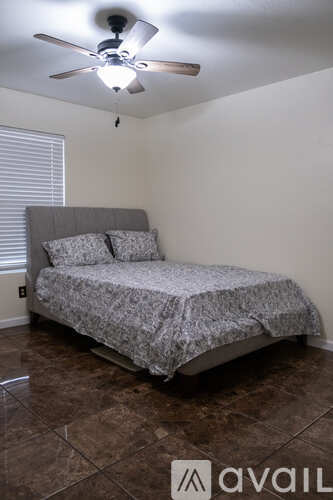 A bedroom with a bed, pillows, and a ceiling fan.