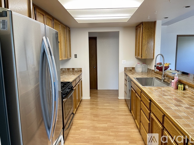 A kitchen with wooden cabinets and a stainless steel refrigerator.