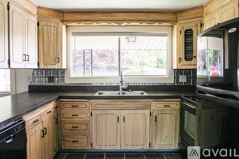 A kitchen with wooden cabinets and black appliances.